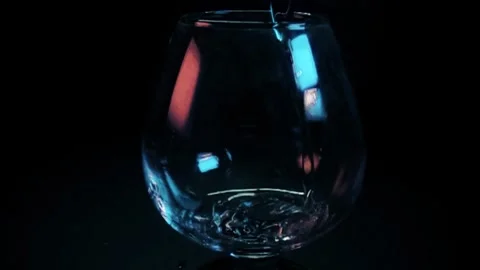Clear liquid pouring into a snifter glass on black background Stock Footage 314852539