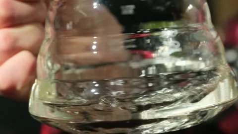 Clear liquid spins inside textured glass container creating whirl Stock Footage 306592520