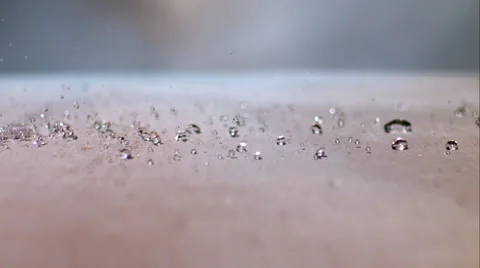 Clear liquid splashes onto beige surface. Sideview. Slow motion. Stock Footage 64887798