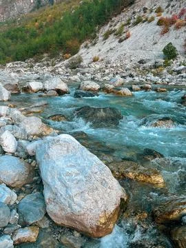 Clear mountain river flowing over colorful rocks in a stony riverbed Stock Photos