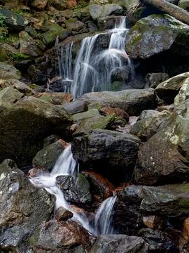 Clear mountain stream flowing over jagged rocks Stock Photos