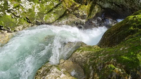 Clear mountain water flows through a rock chute in the rock face.  Stock Footage 266870563
