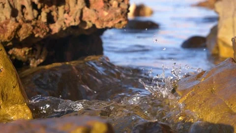 Clear ocean water splashes dynamically between rugged coastal shore rocks. Stock Footage 337406567
