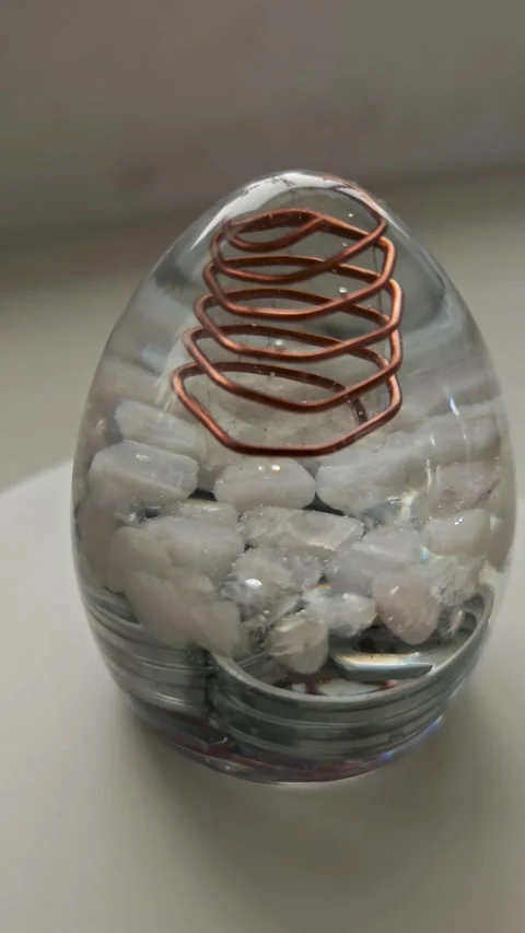 Clear Orgone Energy Egg Sculpture with White Quartz Crystals | Rotating Epoxy Stock Footage 338167656