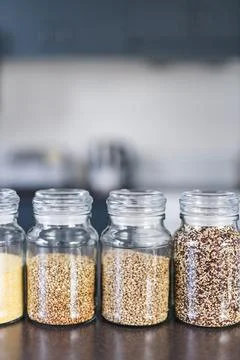 Clear pantry jars with different types of grains and legumes including quin.. Stock Photos