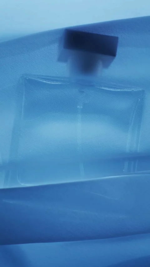 Clear perfume bottle behind blue translucent fabric mesh veil Stock-Footage 331775260