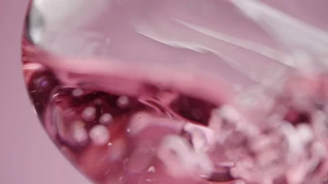 Clear pink liquid pours into a laboratory glass tube, forming bubbles inside Stock Footage 178407818