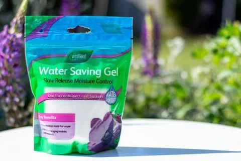 A clear plastic bag of Water Saving Gel on a white table in a garden setting Stock Photos