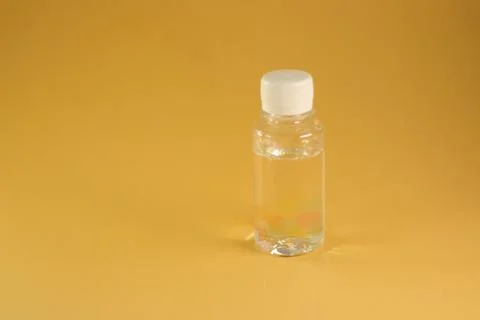 Clear plastic bottle with liquid on and yellow background Stock Photos