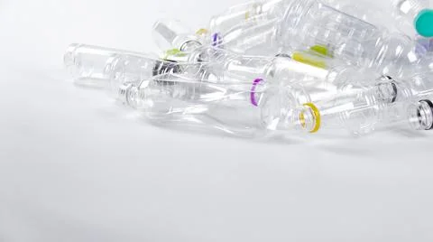 Clear plastic bottles on a white surface, awaiting recycling. Stock Photos