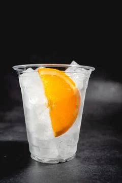 Clear plastic cup containing ice and sliced oranges. Stock Photos