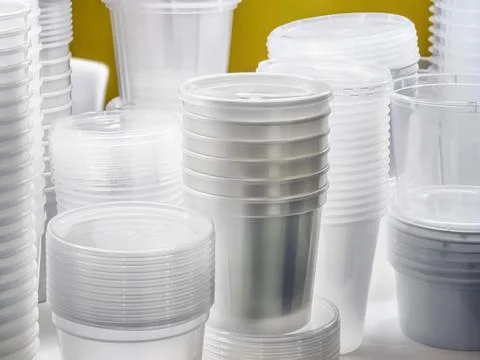 Clear plastic cups and containers stacked neatly on a table in a bright space Stock Photos