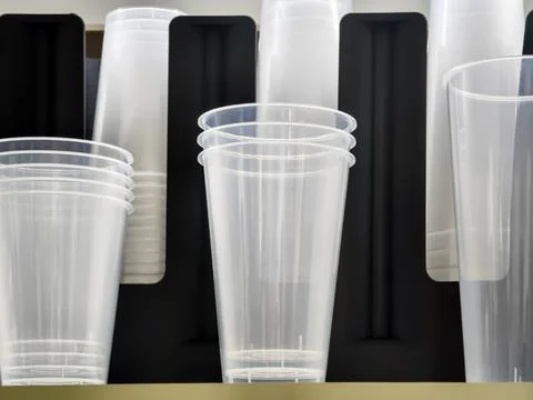 Clear plastic cups are stacked on a shelf in a store ready for use at event.. Stock Photos