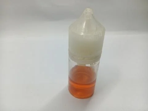 Clear plastic dropper bottle with orange liquid on a white background Stock Photos