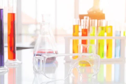 Clear plastic glasses, test tubes in a stand and a microscope on a white ta.. Stock-Fotos
