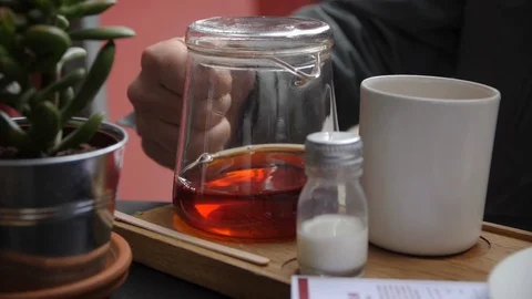 Clear Pot of Black Tea Ready to be Poured in Slow Motion Next to White Cup Stock Footage 89700346