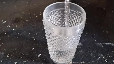 Clear refreshing water pouring into textured glass container motion video Stock Footage 339374462