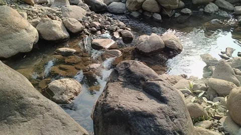 Clear river stream flowing around large stones and boulders under sunlight 스톡 동영상 344087847