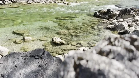 Clear river water flowing over rocks with blurred foreground stones Vídeos de archivo 342024381