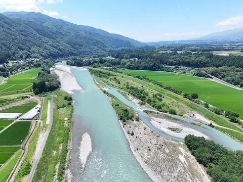 Clear river winds through lush green fields Stock Photos