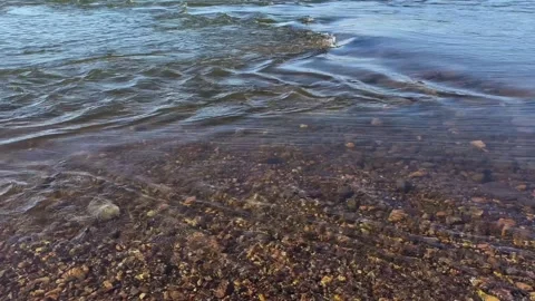 Clear running water of the river with a visible rocky bottom. Video footage of a Stock Footage 332626319