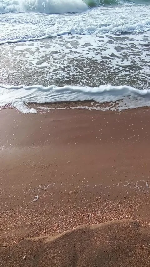 Clear sea water rolls onto the sandy shore in a wave. Vertical mobile video Stock Footage 305761253