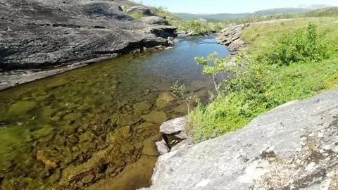 A clear, shallow stream flows through a rocky gorge Stock Footage 321997133