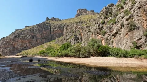 Clear shallow water flowing through rocky canyon on Mallorca island with steep Stock Footage 330803764