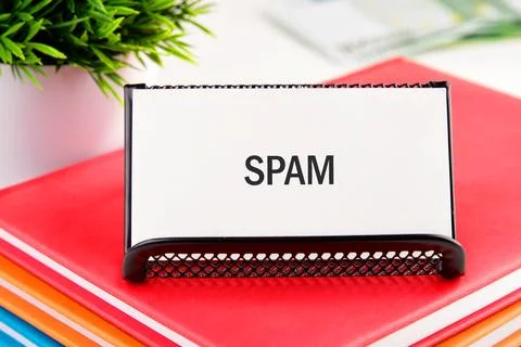 A clear sign reading spam is placed on a desk among vibrant folders and an of Foto stock