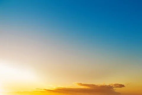 A clear sky featuring a vibrant gradient from deep blue to bright orange du.. Stock Photos