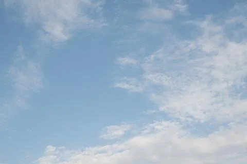 Clear sky with scattered white clouds. The clouds vary in size and shape, cre Stock Photos