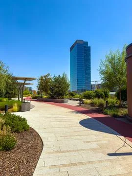 A clear sky shows sunlight over a wide pathway. People walk along the path su Stock Photos