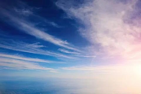 Clear sky with wispy clouds and sunlight over the ocean Stock Photos