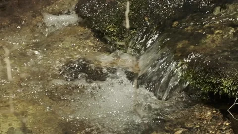 Clear smooth water flows down into tiny bubbling pool, close up slow motion Stock Footage 130617594