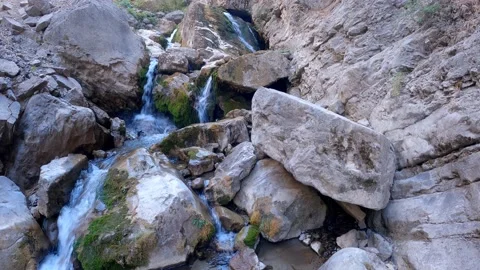 Clear snow water flowing between large and small rocks Video stock 171532092