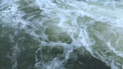 A clear stream with bubbling water flowing through stone boulders. Stock Footage 251705052