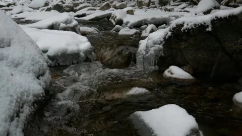 Clear stream water flow over heavy snow rock in a cold winter woodland Video stock 342518846