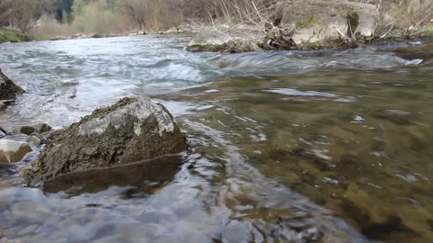 A clear stream of water flows between the stones in the mountains Stock Footage 153506893