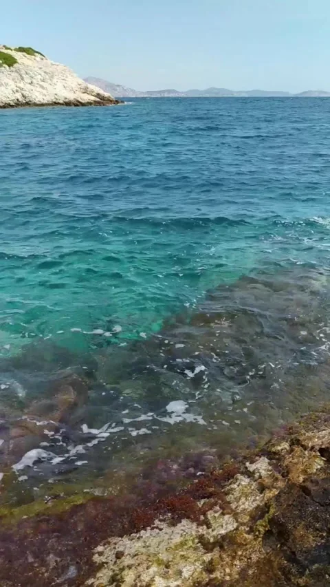 Clear turquoise lagoon with gentle waves hitting a rocky shore Stock Footage 312778906