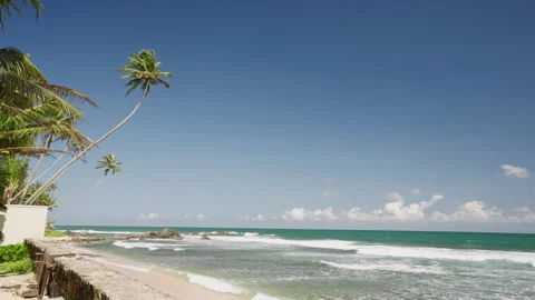 Clear turquoise ocean with churning waves crashing onto sandy beach in afternoon Stock Footage 250558404