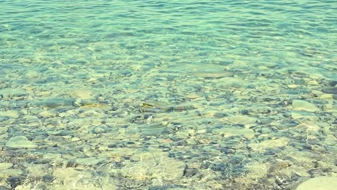 Clear turquoise water gently laps against a smooth stone Stock Footage 344813389