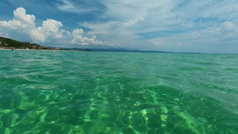 Clear turquoise water ripples gently under a bright sky. Trani Ammouda, Greece Stock Footage 339618587