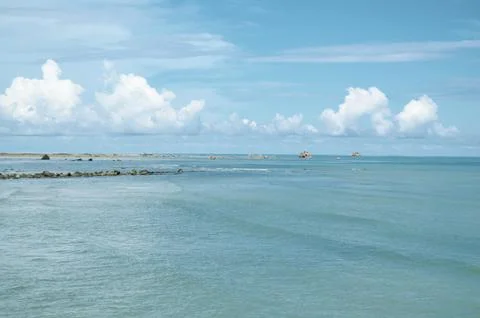 Clear turquoise water scene with distant horizon and fluffy clouds floating.. Stock Photos