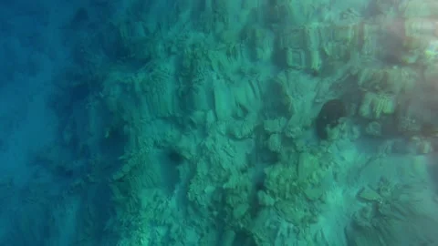 Clear underwater scene reveals rocks, algae, and seabed texture below rippling Stock Footage 339980304