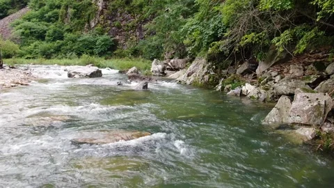 Clear valley water flowing under the caving mountains_1 Stock Footage 280179319