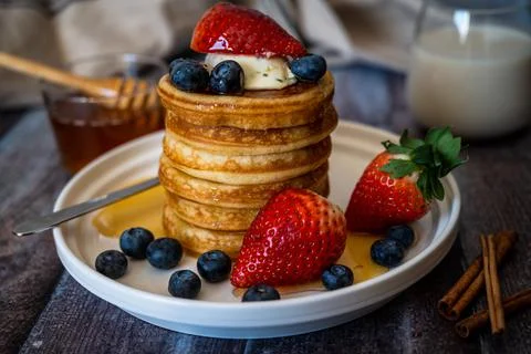 Clear view of Stack of pancakes with honey stick, strawberry, blue berry and  Stock Photos