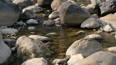 Clear water flowing over large boulders in a rocky river bed Stock Footage 342957658