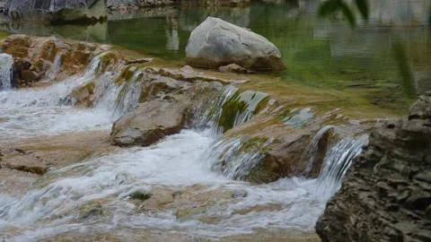 Clear water flowing over mossy rocks in a peaceful forest mountain stream Stock Footage 342310071
