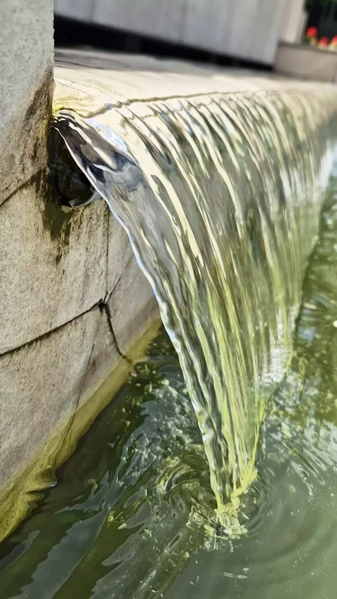 Clear Water Flowing Smoothly Over Stone Edge in Modern Garden Fountain Stock-Footage 339078016