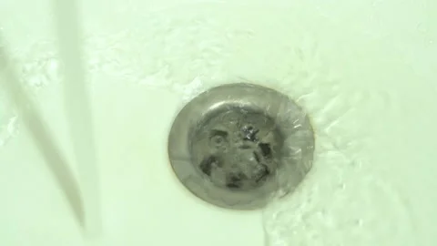Clear water flows down the drain hole in the white sink into the drain Stock Footage 155678600